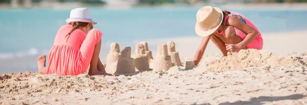 Zwei Mädchen bauen Sandburg am Strand