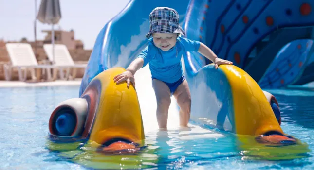 Kleines Kind auf Wasserrutsche im Wasserpark eines Campingplatzes