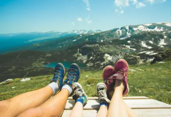 Ansicht der Beine einer Familie mit Wanderschuhen im Hintergrund Bergpanorama