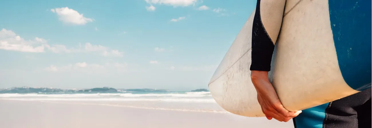 Surfer mit Surboard unter dem Arm am Strand