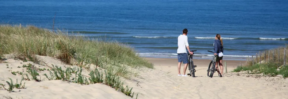 Paar mit Fahrrädern an sandigem Strand mit Blick auf das Meer