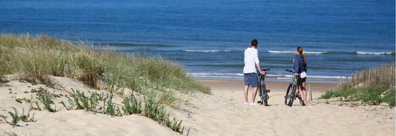 Paar mit Fahrrädern an sandigem Strand mit Blick auf das Meer