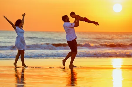 Glückliche Familie am Strand bei untergehender Sonne