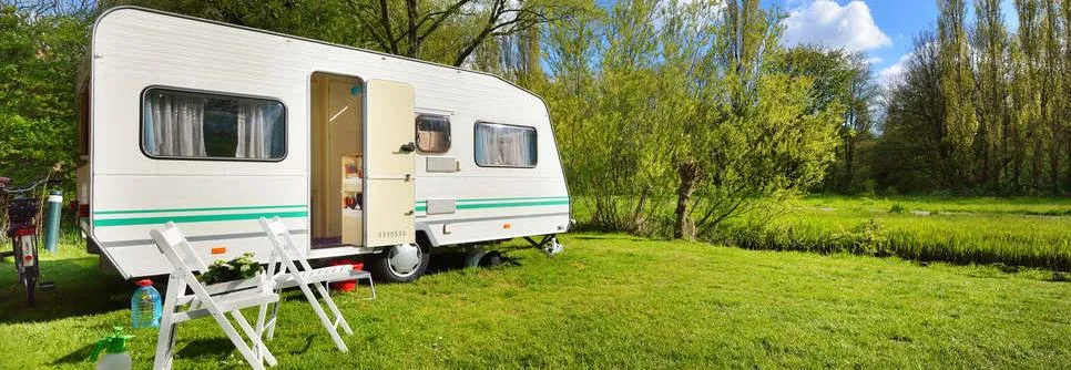 Wohnwagen auf grüner Wiese an sonnigem Tag
