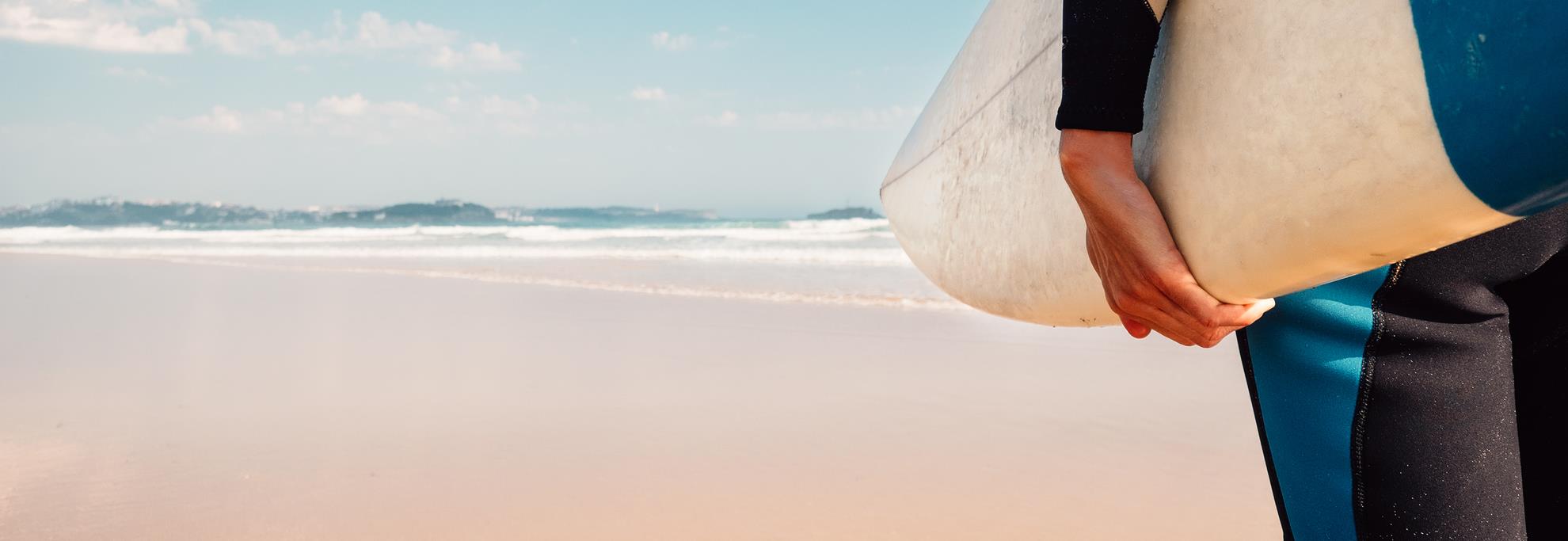 Surfer mit Surboard unter dem Arm am Strand