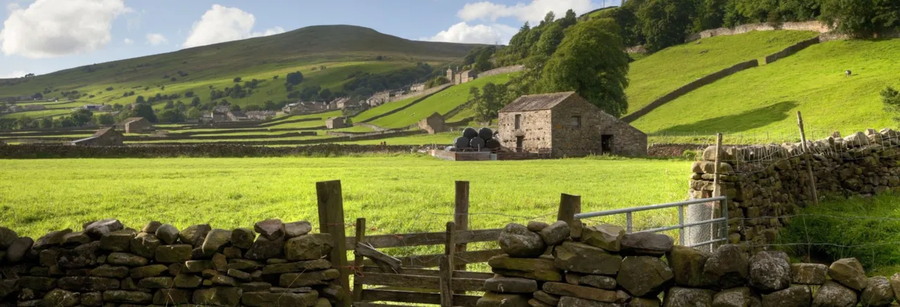 Hügelige Landschaft mit Steinmauer und altem Steinhaus in Yorkshire, England