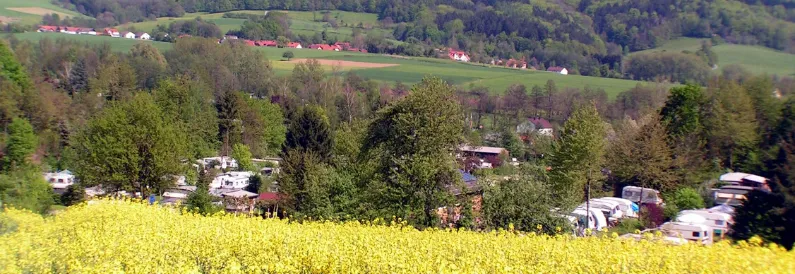 Campingplatz in hügeliger Landschaft mit gelb blühender Wiese