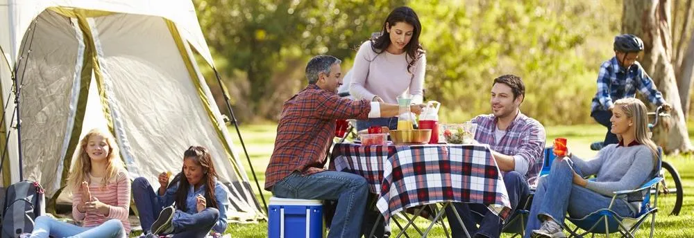 Familien beim gemeinsamen Essen vor Campingzelt