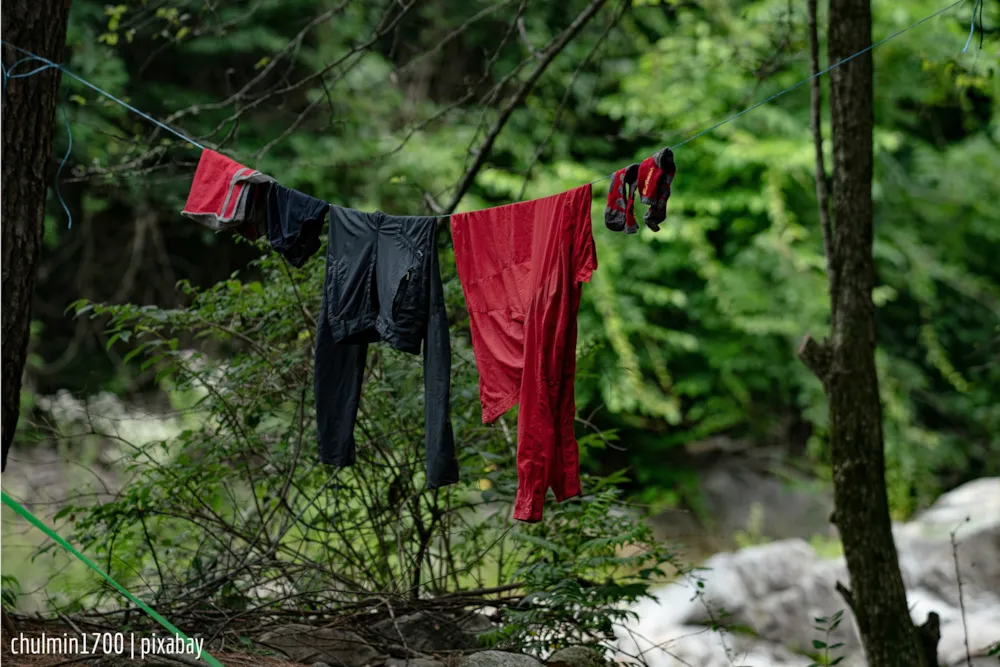 Nasse Kleidung hängt über einer improvisierten Wäscheleine im Wald