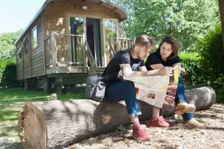 Paar sitzt entspannt mit Stadtplan vor einem Planwagen