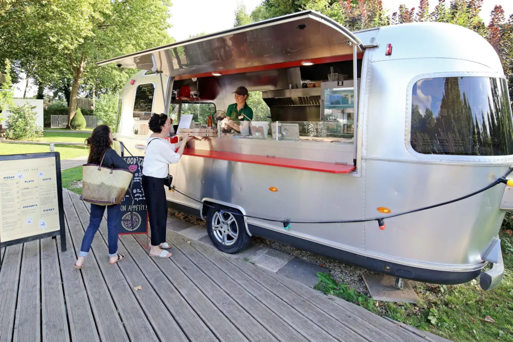 Campinggäste vor einem silbernen Food-Truck