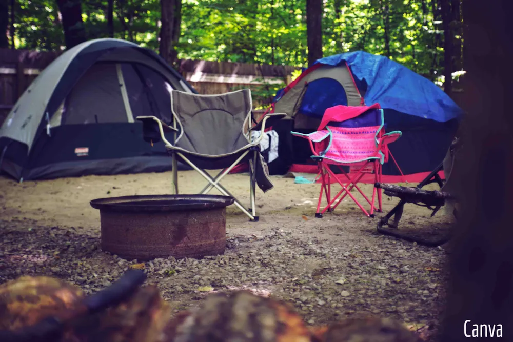 Zwei Klappstühle vor Campingzelten im Wald