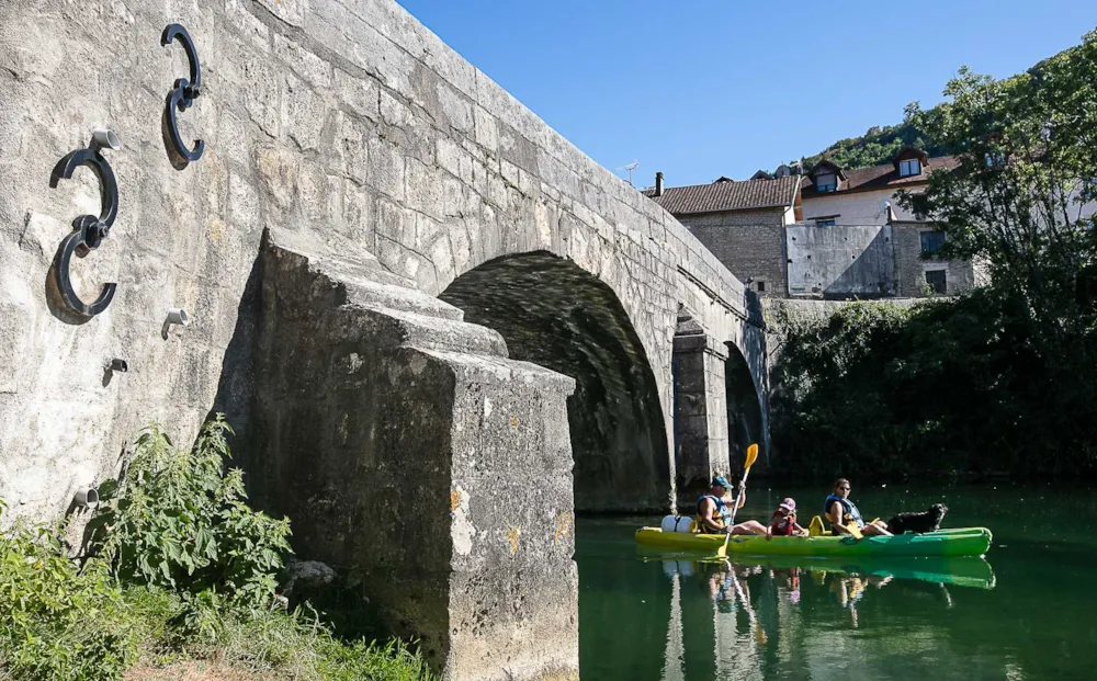 Familie im Kanu auf Fluss unter einer Brücke