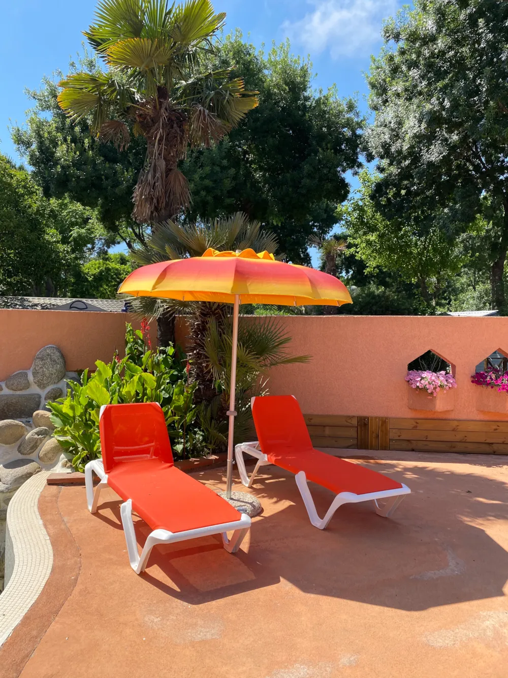 Liegestühle und Sonnenschirm am Pool