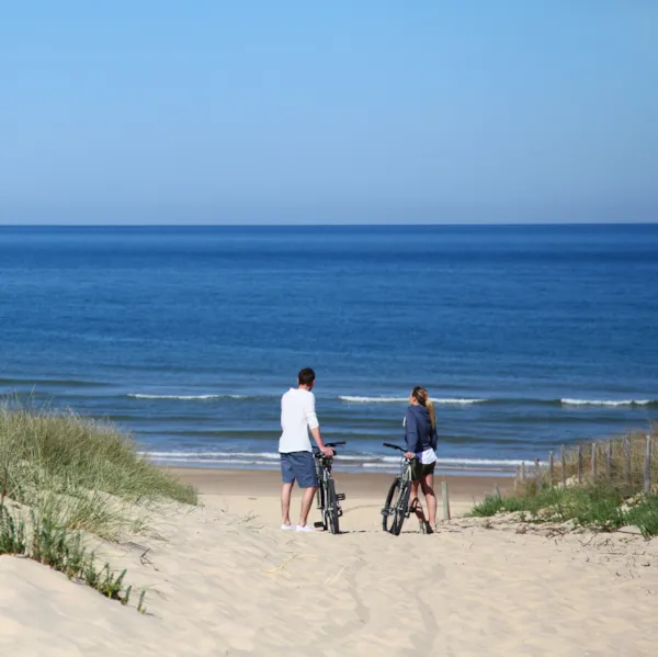 Paar mit Fahrrädern an sandigem Strand mit Blick auf das Meer