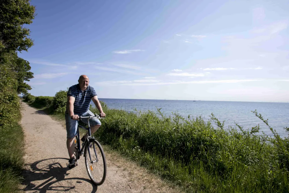 Mann fährt auf dem Rad am Wasser entlang