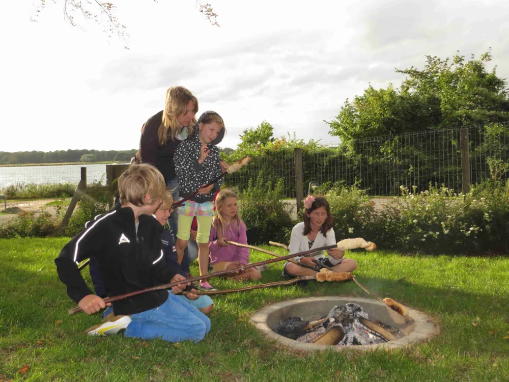Familie sitzt am Lagerfeuer mit Stockbrot