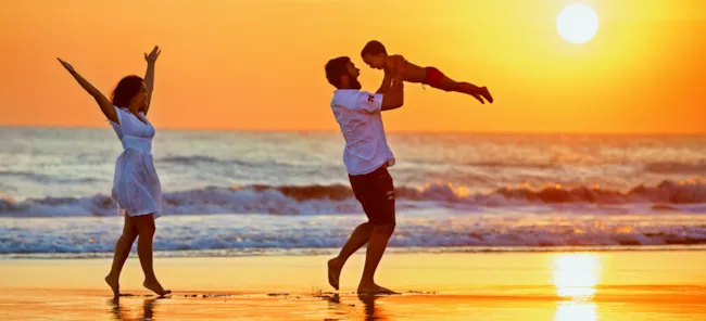 Glückliche Familie am Strand bei untergehender Sonne