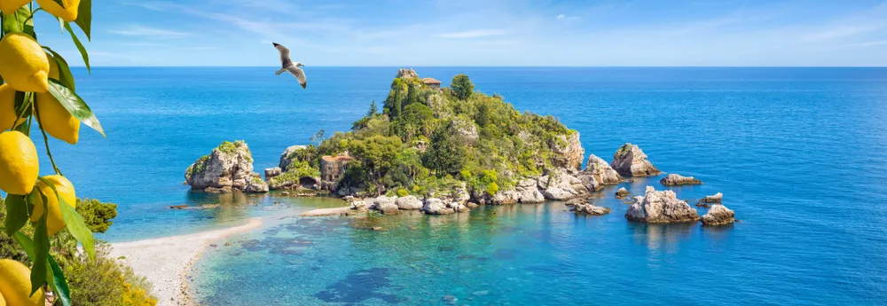 Kleine Insel umgeben von türkisblauem Meer bei Taormina auf Sizilien