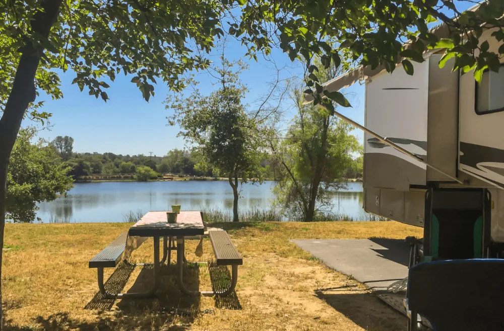 Wohnwagen auf Stellplatz mit Picknickecke am See