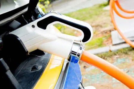 Nahaufnahme eines Elektroautos angeschlossen an eine Ladestation