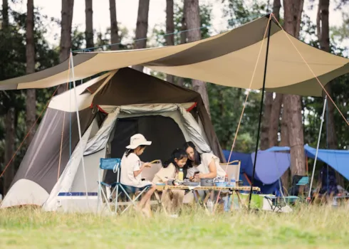 Mutter mit Kindern vor einem Campingzelt