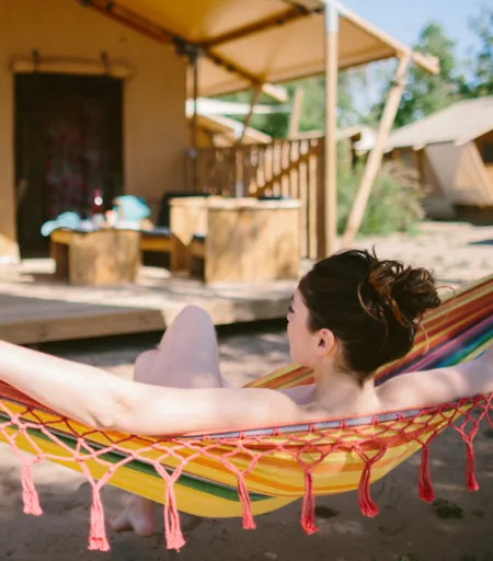 Vacancière se relaxant dans un hamac devant un hébergement de camping - Naturisme.fr