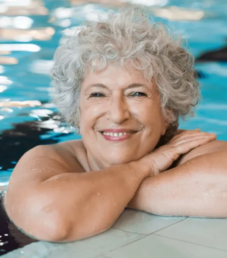 Portrait d'une femme souriante dans une piscine - Naturisme.fr