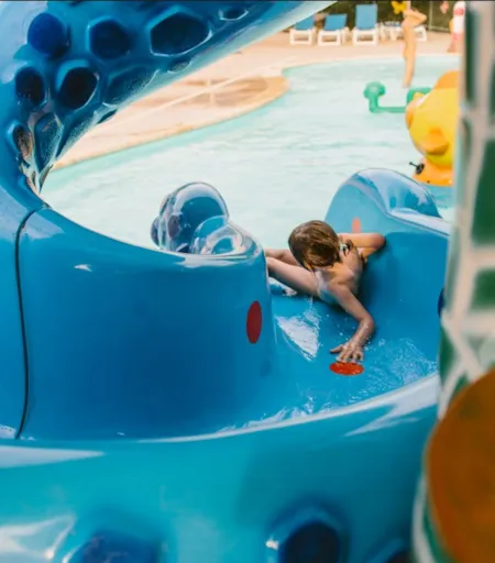 Enfant jouant dans une aire de jeux aquatique d'un camping - Naturisme.fr