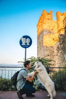 Junger Mann mit Hund in Sirmione genießt den Sonnenuntergang, Lombardei, Italien
