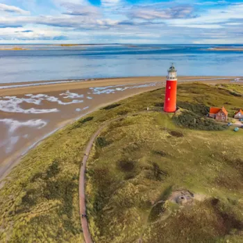 Vanuit de hoogte een zicht op de Waddenzee, het strand en de rode vuurtoren op het eiland Texel | Camping Direct