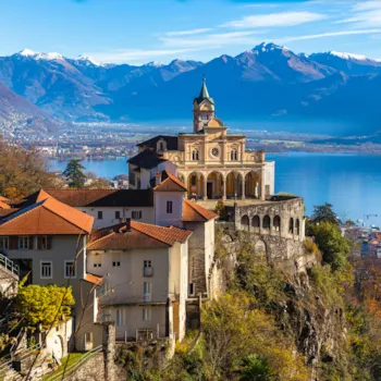 oramablick in der Nähe der Kirche Madonna del Sasso oberhalb der Stadt Locarno mit dem Lago Maggiore, dem schneebedeckten Gipfel der Schweizer Alpen und einer blauen Wolkenformation am Himmel im Hintergrund, Tessin, Schweiz