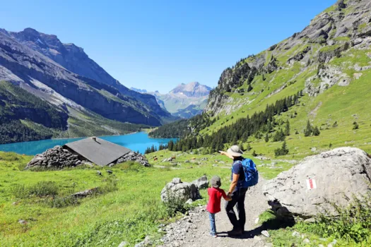 Familienbeim Wandern in den Schweizer Alpen vor Berpanoram mit See