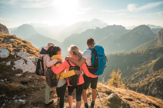 Eine Familie beim Wandern, die sich umarmt und über das Bergpanorama der Julischen Alpen blickt, Slowenien