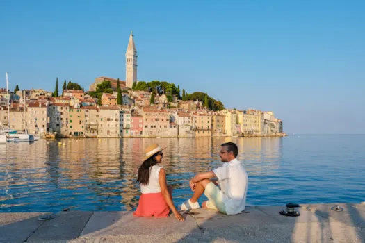 Paar, das am Ufer von Rovinj in Kroatien entspannt, während die Sonne über der Küstenstadt untergeht, Kroatien