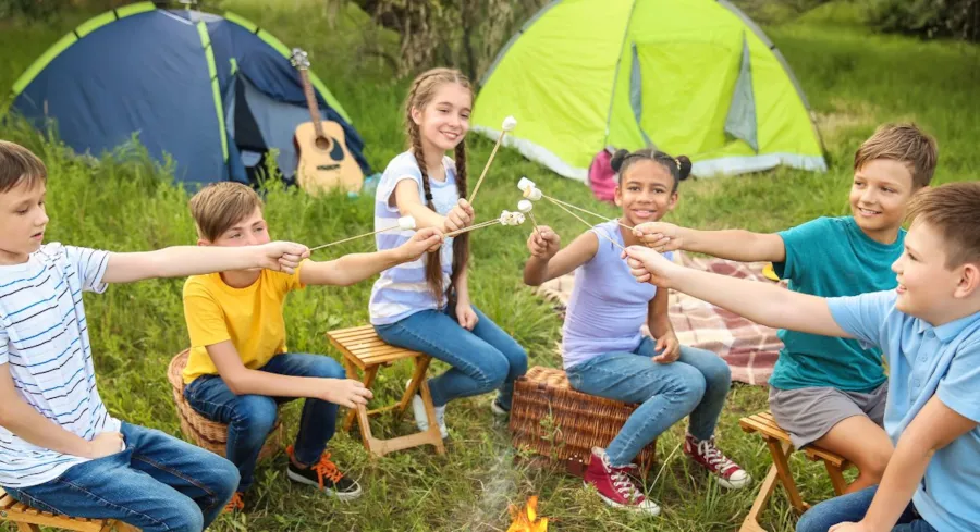 Kinder rösten Marshmallows an einem Lagerfeuer auf einem Zeltplatz