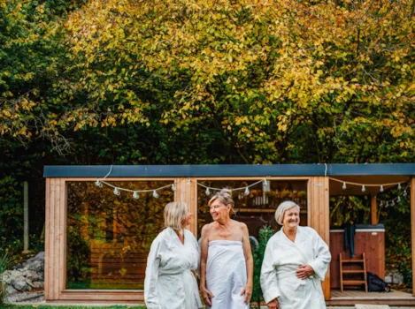 Drei gutgelaunte Damen in Bademänteln vor schickem Mobilheim