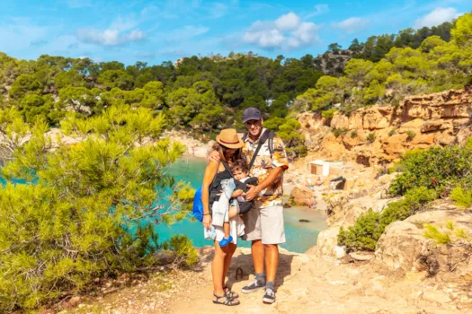 Urlaubsfoto einer Familie mit Baby in der Trage am Playa Salada und Saladeta an der Küste von Ibiza, Spanien