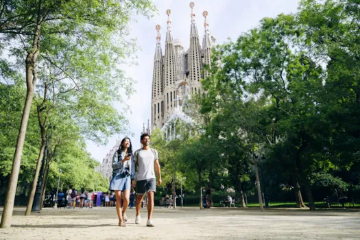 Junges Paar, das Händchen hält, beim Spaziergang durch Barcelona, im Hintergrund die Sagrada Família