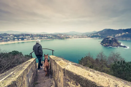 Tourist mit seinem Hund auf Aussichtsplattform mit Blick über San Sebastian, Spanien