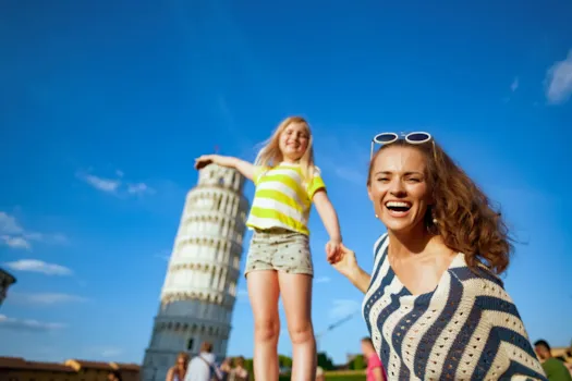 Lächelnde und ihre Tochter posieren für ein Touristenfoto vor dem Schiefen Turm von Pisa, Italien