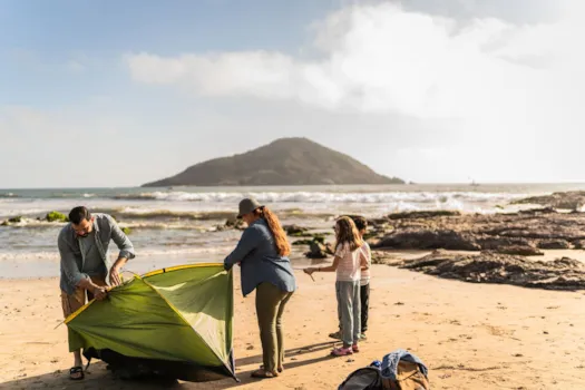 Familie beim Aufbau eines Zeltes am Strand in der Bretagne, Frankreich