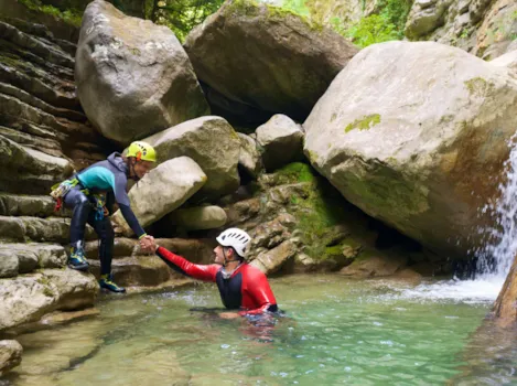 Frau hilft Mann aus dem Wasser beim Canyoning