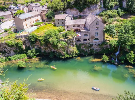 Blick auf das Dorf Saint-Chély-du-Tarn und Kanufahrer auf dem Fluss Tarn im gleichnamigen Tal in Lozère