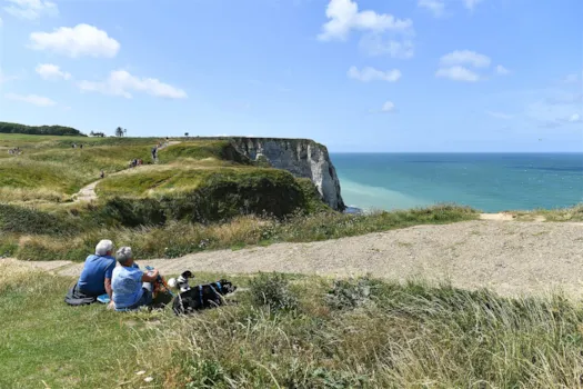 Wanderer mit Hund ruhen sich auf einer Klippe aus, Étretat, Normandie, Frankreich.