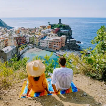 Päarchen sitzt am Berg und blickt auf malerisches Küstendorf Vernazza, Cinque Terre, Italien