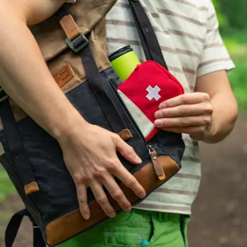 Wanderer, der während einer Wanderung im Wald sein Erste-Hilfe-Set in seinen Rucksack packt