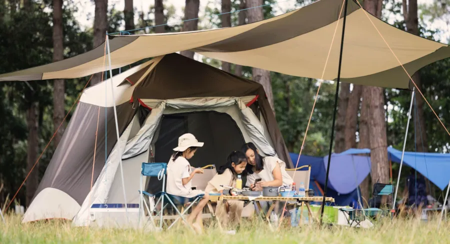 Mutter mit Kindern vor einem Campingzelt
