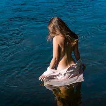 Junge Frau badet nackt im See