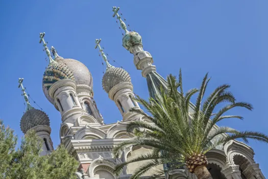 Blick auf die Türme der Chiesa San Basilio vor blauem Himmel mit Palme, Sanremo, Ligurien Italien